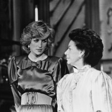 Prince Charles in a dark suit standing next to Princess Diana and Princess Margaret looking at each other